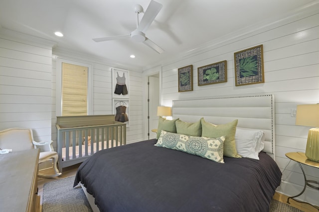 bedroom featuring ceiling fan, wooden walls, and hardwood / wood-style floors