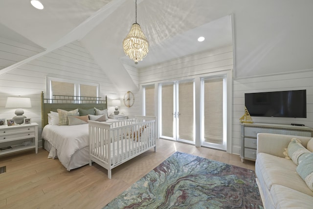 bedroom featuring vaulted ceiling with beams, wooden walls, light hardwood / wood-style floors, and a notable chandelier