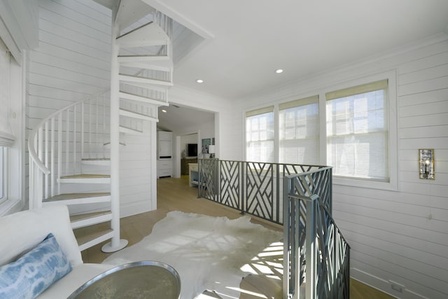 stairway with wood walls, hardwood / wood-style floors, lofted ceiling, and ornamental molding