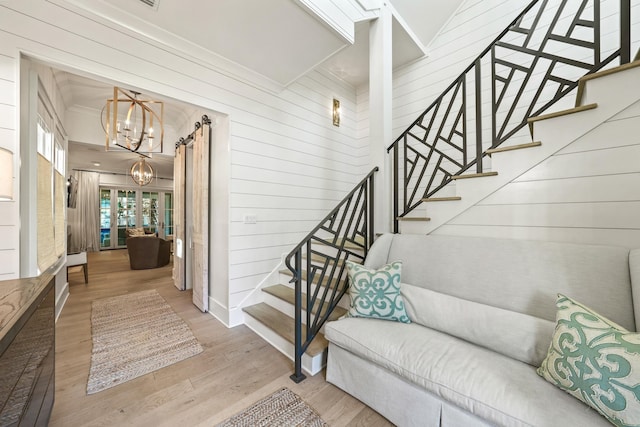 stairs featuring an inviting chandelier, wood walls, and wood finished floors