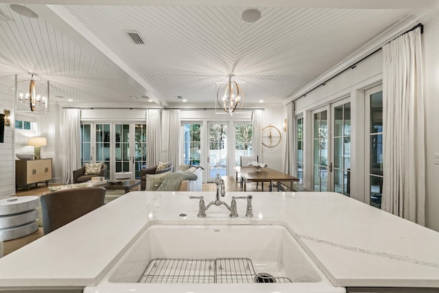 kitchen featuring french doors, open floor plan, a notable chandelier, and a sink