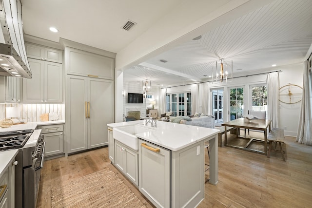 kitchen featuring visible vents, a sink, a center island, double oven range, and a notable chandelier
