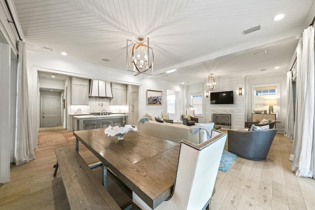 dining space with recessed lighting, visible vents, a fireplace, light wood-style flooring, and a notable chandelier