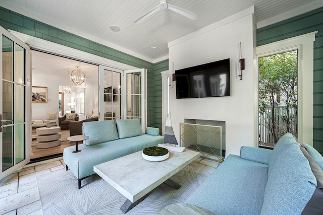living room featuring ceiling fan with notable chandelier, a fireplace, and crown molding