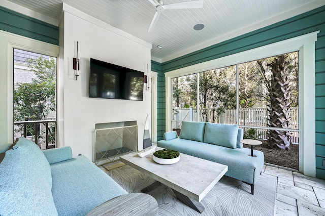 living area with a ceiling fan, stone tile flooring, and a wealth of natural light