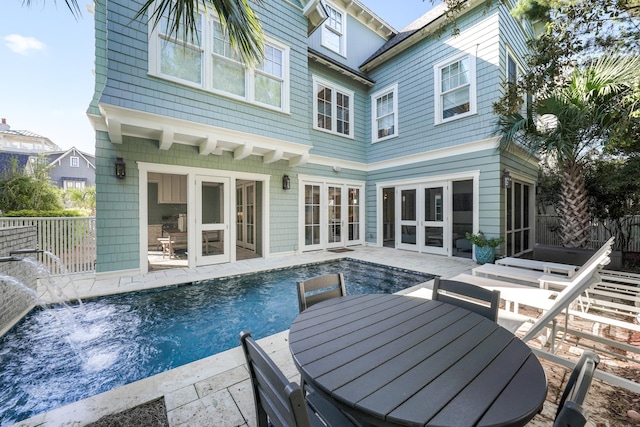 rear view of property featuring a fenced in pool, fence, outdoor dining area, french doors, and a patio
