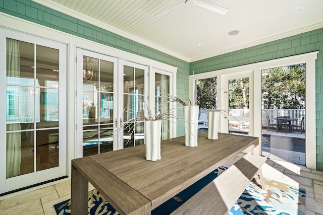 sunroom / solarium with stone tile flooring, ornamental molding, outdoor dining space, and ceiling fan