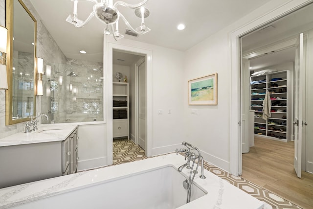 full bath featuring recessed lighting, a spacious closet, vanity, a freestanding tub, and a stall shower