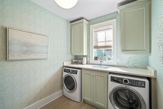 laundry room with light wood finished floors, a sink, washer / clothes dryer, and cabinet space