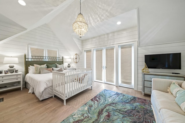 bedroom featuring wooden walls, wood finished floors, vaulted ceiling with beams, access to outside, and a notable chandelier
