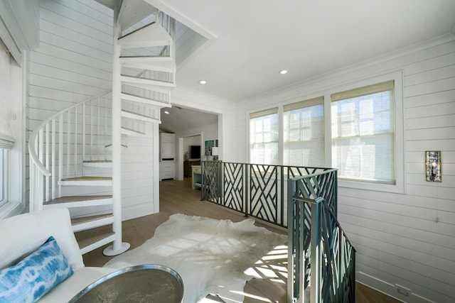 staircase with wood finished floors, wood walls, and crown molding