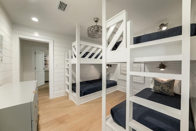 bedroom featuring light wood finished floors, visible vents, recessed lighting, and wood walls