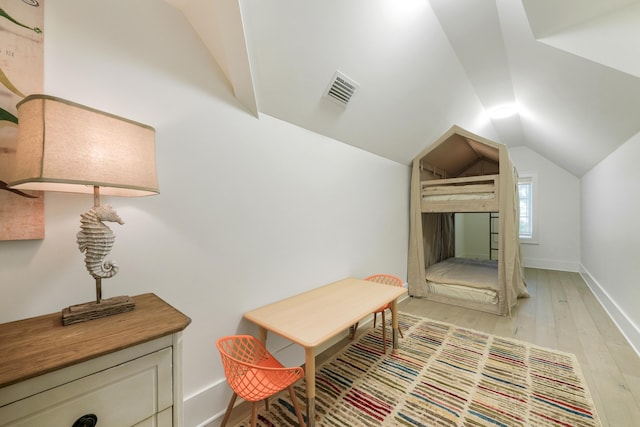 interior space featuring light wood-style floors, vaulted ceiling, visible vents, and baseboards
