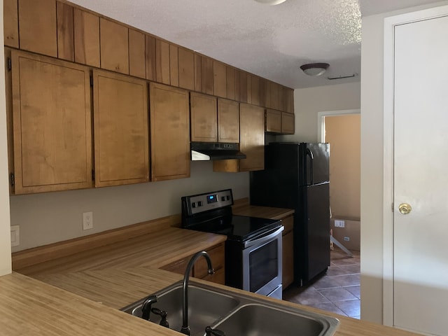 kitchen with a textured ceiling, stainless steel electric range, sink, and tile patterned flooring