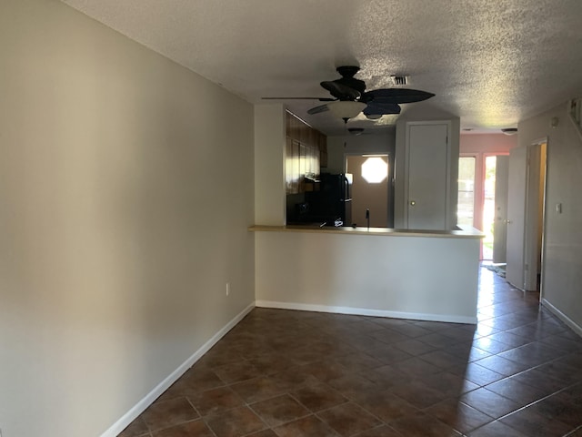 kitchen with dark tile patterned flooring, black fridge, ceiling fan, a textured ceiling, and kitchen peninsula