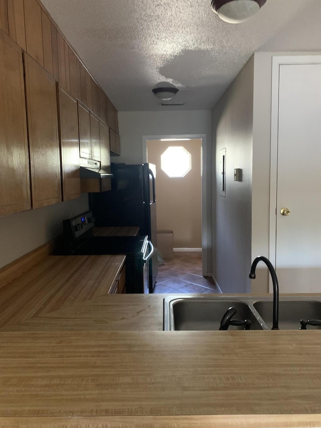 kitchen featuring stove, wooden counters, a textured ceiling, and sink