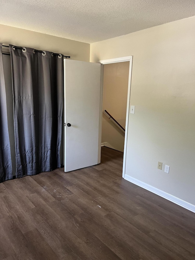 spare room featuring dark hardwood / wood-style flooring and a textured ceiling