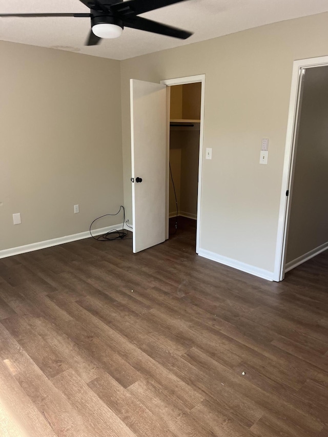 unfurnished bedroom with ceiling fan, dark hardwood / wood-style floors, and a walk in closet