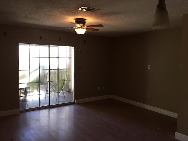 empty room with ceiling fan, dark hardwood / wood-style flooring, and a textured ceiling