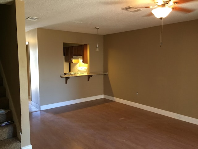 empty room with ceiling fan, dark wood-type flooring, and a textured ceiling