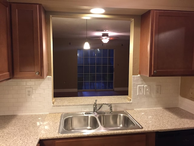 kitchen with sink, ceiling fan, light stone countertops, tasteful backsplash, and decorative light fixtures