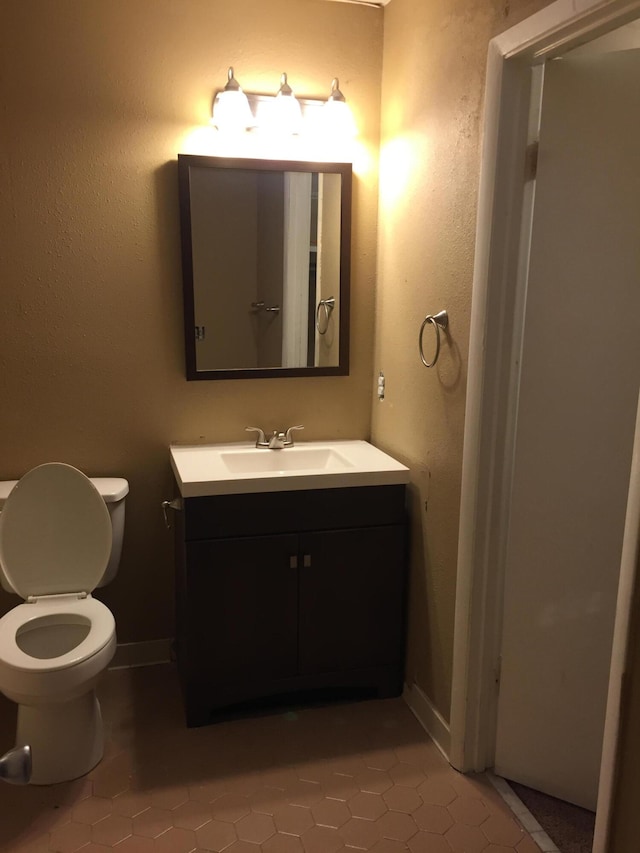 bathroom featuring tile patterned flooring, vanity, and toilet