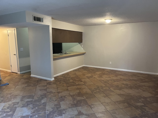 interior space featuring kitchen peninsula, dark brown cabinets, a textured ceiling, and sink