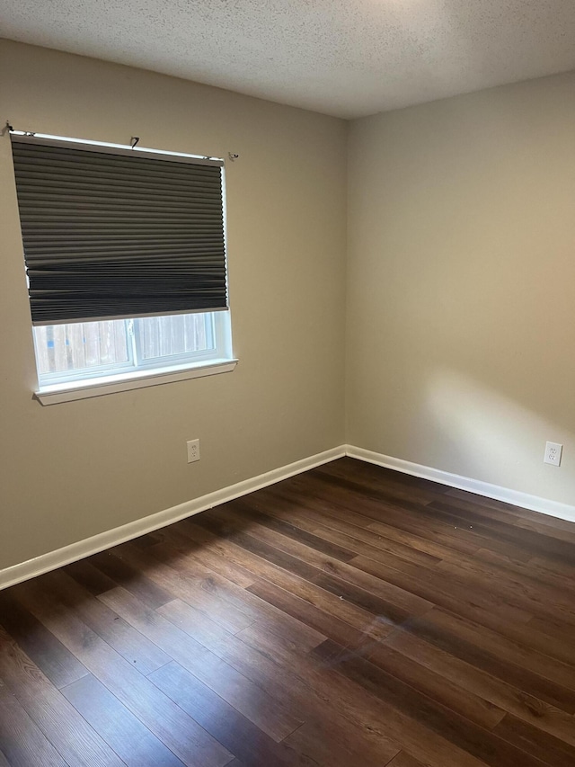 empty room featuring a textured ceiling and dark wood-type flooring