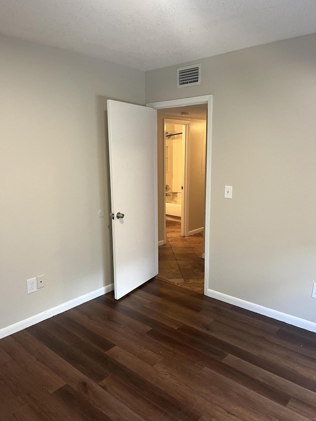 unfurnished room featuring a textured ceiling and dark hardwood / wood-style floors