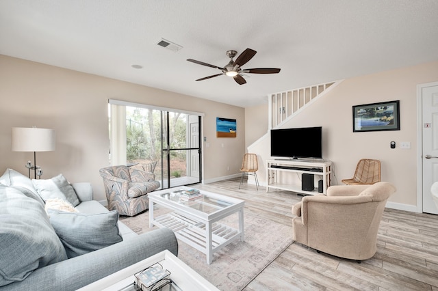 living room with ceiling fan, light hardwood / wood-style flooring, and a textured ceiling