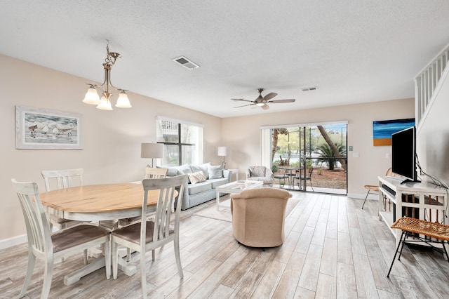 dining area with ceiling fan with notable chandelier, a healthy amount of sunlight, light hardwood / wood-style floors, and a textured ceiling