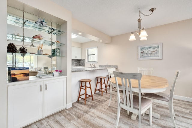 dining room featuring sink, light hardwood / wood-style flooring, and an inviting chandelier