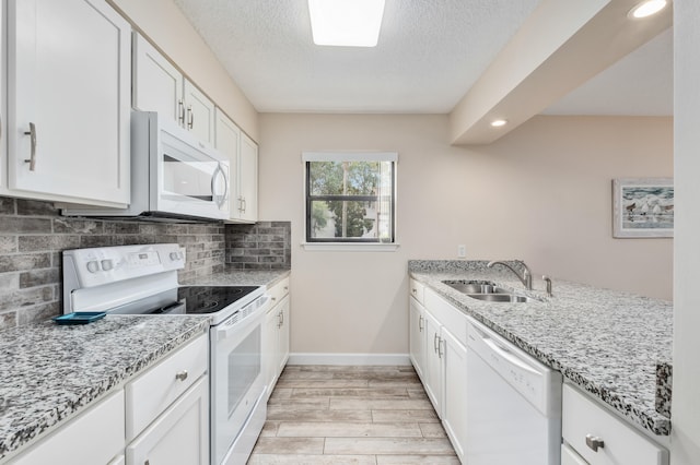 kitchen featuring light stone counters, white appliances, sink, light hardwood / wood-style flooring, and white cabinets