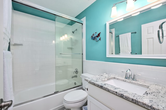 full bathroom featuring vanity, toilet, tile walls, and bath / shower combo with glass door