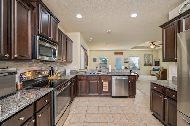 kitchen with sink, hanging light fixtures, backsplash, light tile patterned floors, and appliances with stainless steel finishes