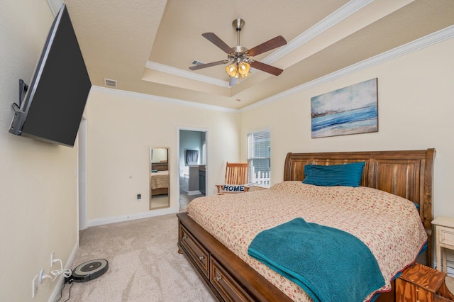 bedroom featuring ensuite bathroom, ornamental molding, light colored carpet, a raised ceiling, and ceiling fan