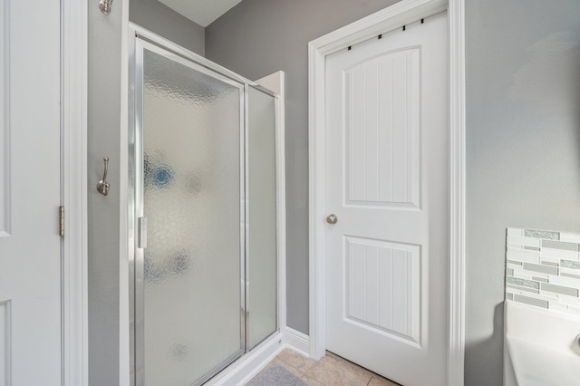 bathroom featuring backsplash, tile patterned floors, and a shower with door