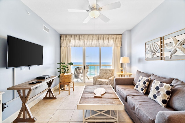 living room featuring ceiling fan, a water view, and light tile patterned floors