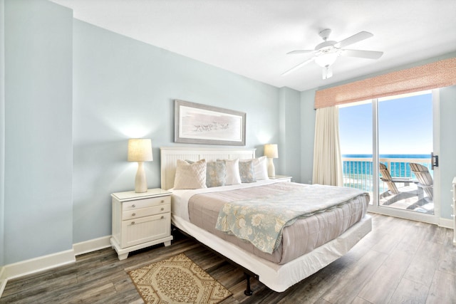 bedroom with access to exterior, ceiling fan, a water view, and dark wood-type flooring