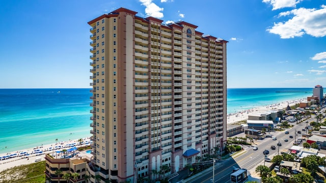 view of building exterior featuring a water view and a beach view