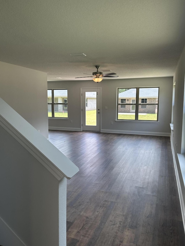 unfurnished living room featuring ceiling fan, dark wood-type flooring, and a textured ceiling