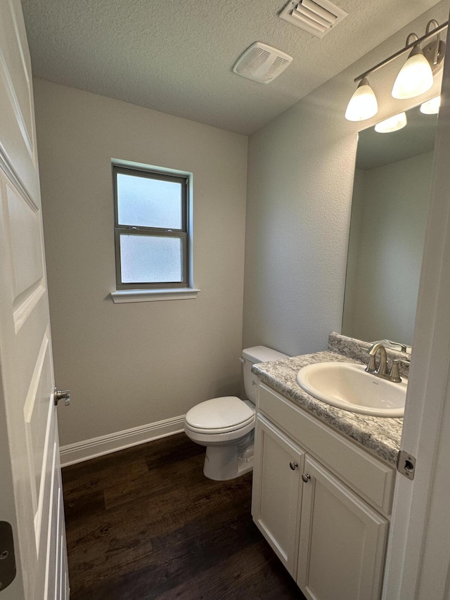 bathroom featuring hardwood / wood-style floors, vanity, a textured ceiling, and toilet