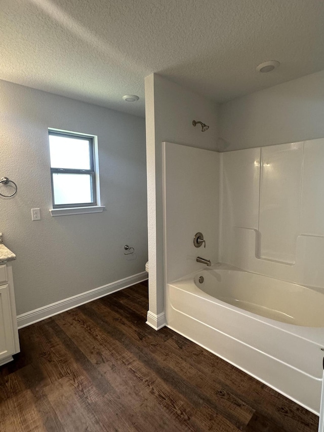 full bathroom with vanity, shower / tub combination, hardwood / wood-style flooring, toilet, and a textured ceiling