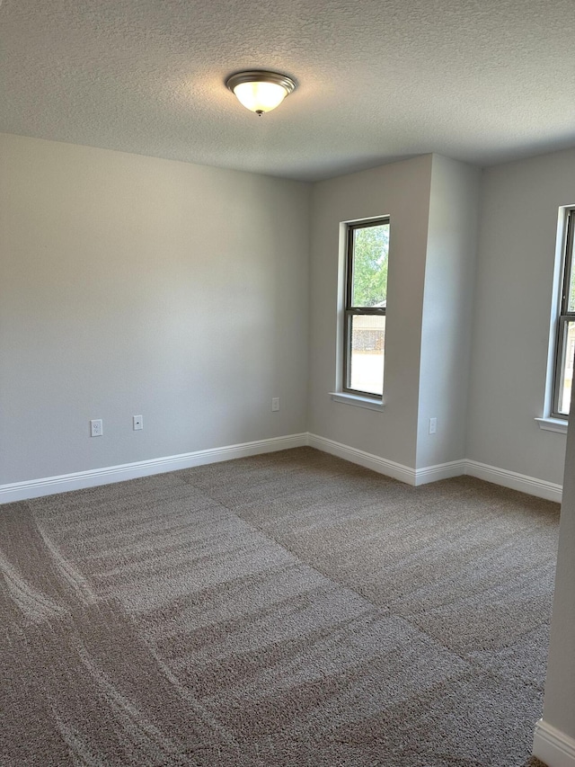 carpeted empty room featuring a textured ceiling