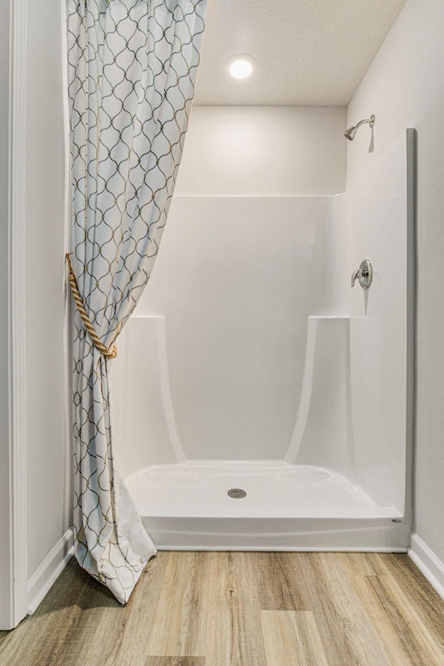 full bath with a textured ceiling, wood finished floors, and a shower with curtain