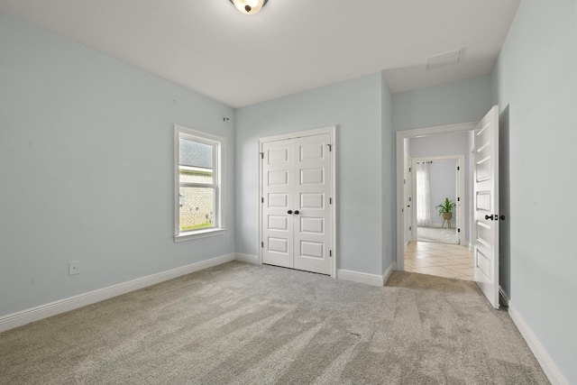 unfurnished bedroom featuring a closet and light colored carpet