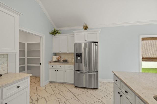 kitchen with stainless steel fridge with ice dispenser, backsplash, white cabinetry, and light stone counters