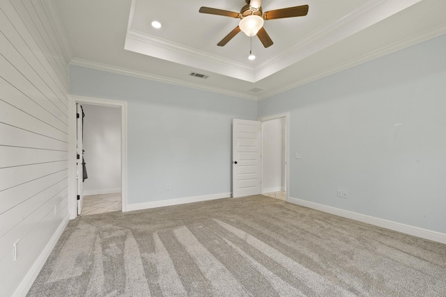 spare room with ceiling fan, a raised ceiling, light colored carpet, and ornamental molding