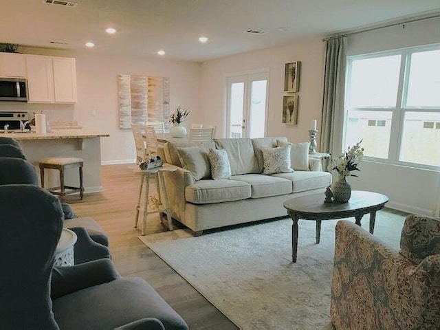 living room with recessed lighting, visible vents, baseboards, french doors, and light wood-type flooring