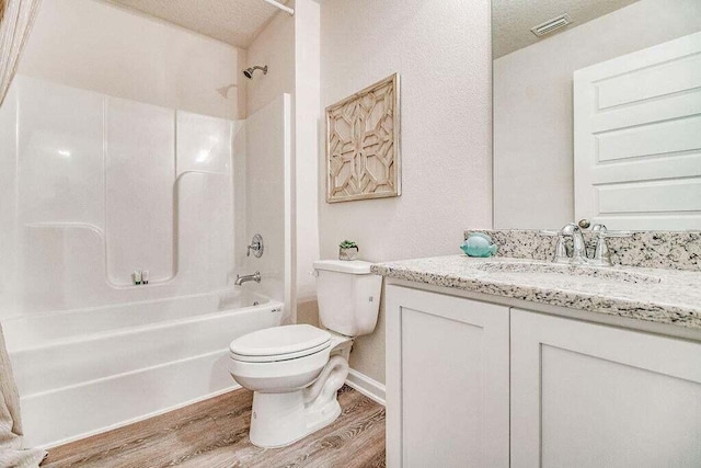 bathroom with visible vents, toilet, wood finished floors, vanity, and shower / washtub combination